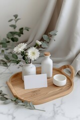 Elegant minimalist home decor composition with blank card displayed on wooden tray alongside white flowers, ceramic accessories, and soft natural textiles