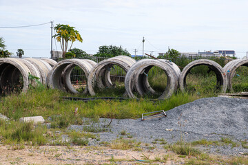 Large concrete drainage pipes arranged outdoors in grassy construction site environment