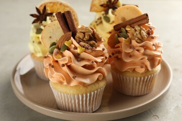 Delicious cupcakes with colorful cream, spices and nuts on grey table, closeup