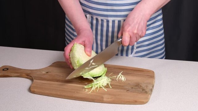 Cooking. A woman's hands chop cabbage on the kitchen counter. 4K video