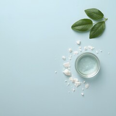 Top view of glass water cup with ice cubes and green leaves on light blue background, symbolizing freshness, hydration, purity, and clean natural wellness concept for health, spa, and eco-friendly des