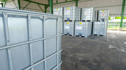 Square-shaped chemical storage tanks with reinforced steel frame for load support, placed in a warehouse awaiting shipment,