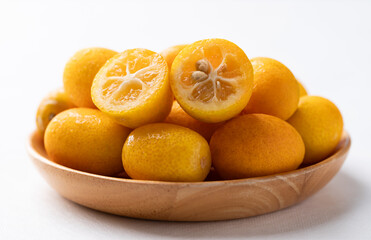 Fresh kumquats fruit on wooden plate with white background