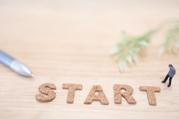 ビジネスマンのミニチュアと、アルファベットでSTARTの文字。