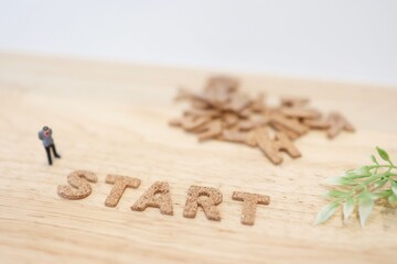ビジネスマンのミニチュアと、アルファベットでSTARTの文字。