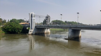 Wide river with bridge view and cloudy sky in urban landscape.