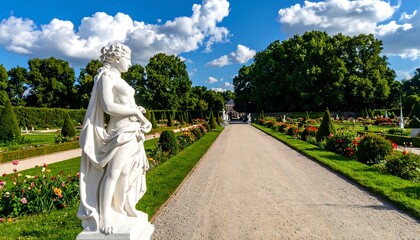 Obraz premium Formal garden pathway lined with sculpted figures and vibrant flowerbeds