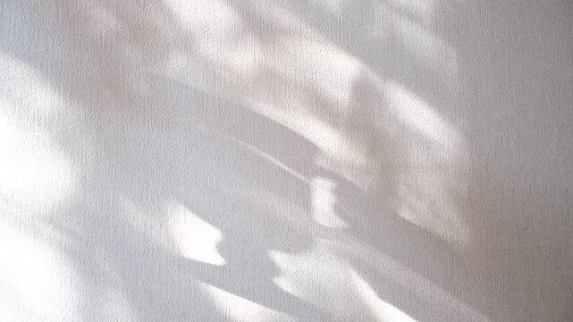 Shadow of woman holds cup, drinking coffee, abstract shadows on white wall. Cozy home or cafe.  Aesthetic background in minimalist. Cinematic atmospheric mood. Morning light creating a warm atmosphere