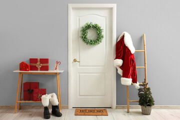 Obraz premium White door with wreath, Santa costume and Christmas gifts near color wall at home