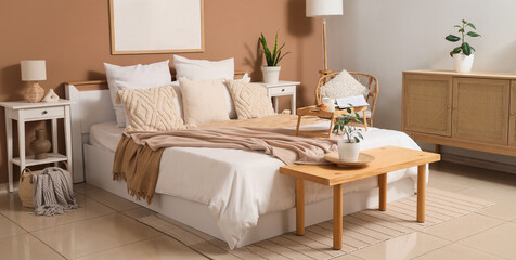 Interior of cozy bedroom with big bed, wooden bench and tables