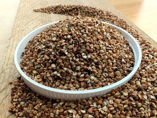 Raw buckwheat in a white bowl on a wooden surface
