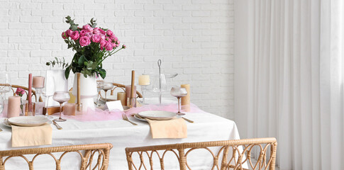Beautiful table setting with pink roses and candles for wedding celebration in room