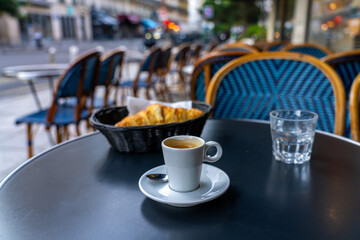 Espresso and croissant at a Parisian cafe table.