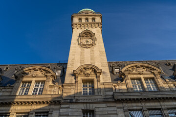 Ornate building facade with clock tower under blue sky.