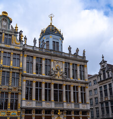 Fototapeta premium Ornate buildings with gold accents and statues under a cloudy sky.