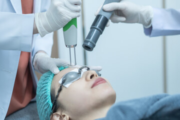 Asian woman wearing protection glasses getting laser skin face treatment.
