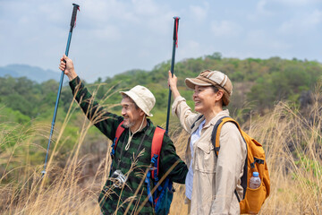 bonding happy senior couple with backpack and trekking poles enjoying the nature,hiking on the mountain and exploring in the forest together