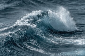 Dramatic ocean wave cresting with foamy white spray against a dark blue sea