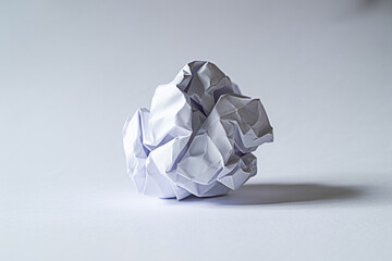 Crumpled paper ball on a white surface symbolizing frustration and creative block in the design process