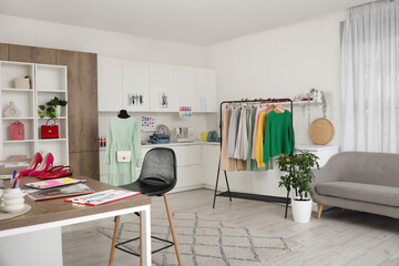 Interior of stylish studio with designer workplace, clothes rack and mannequin