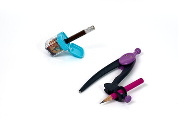 A drawing compass and a pencil sharpener with shavings, tools for geometry and technical drawing, isolated on a white background.