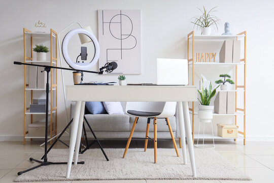 Interior of blogger's office with workplace, laptop, lamp and microphone on table