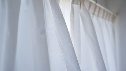 Soft white translucent curtains with light filtering through, creating a calm and airy home interior background.