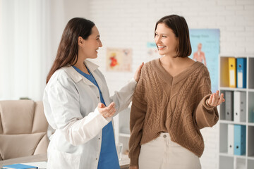 Obraz premium Happy young female doctor with patient in clinic