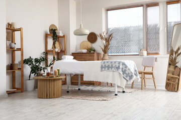 Interior of massage therapist's office with couch, shelving units and spa set on table in modern medical centre
