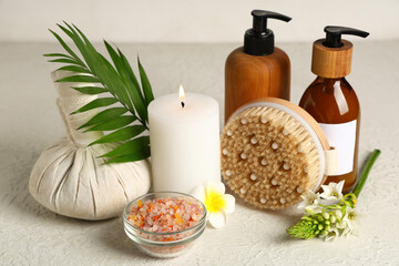 Composition with cosmetic products, spa accessories and burning candle on light table