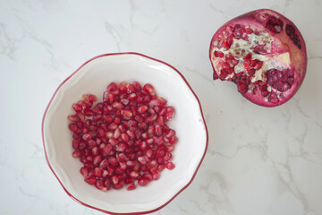 Fresh pomegranate seeds in a bowl on a marble surface