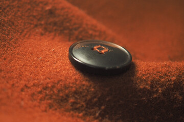 Button resting on soft orange fabric surface