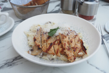 Delicious grilled chicken pasta on white plate with garnish