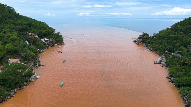 Agua cafe de un rio que proviene de las monta&ntilde;as selvaticas al sur de puerto vallarta en el pueblo de boca de tomatlan despue de las lluvias, el agua cafe choca con el agua azil del mar 