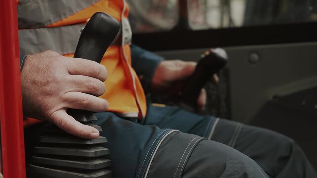 A close-up of the hands of a worker operating a joystick. Controls of heavy construction equipment. The operator controls an excavator.