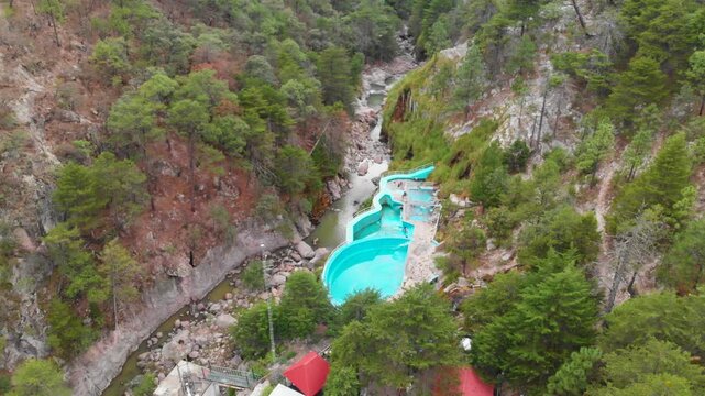 Toma titl down y cenital de las aguas termales de Recowata en chihuahua, albercas azules en medio de un ca&ntilde;on con bosque de pinos verdes