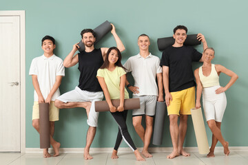 Naklejka premium Group of sporty young people with yoga mats near green wall