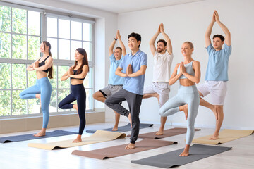 Fototapeta premium Group of sporty young people practicing yoga at gym