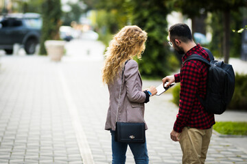 Obraz premium Young man and woman collaborating outdoors, utilizing modern technology in a natural setting. They are standing and engaging over a digital tablet, showcasing teamwork and communication on a pleasant