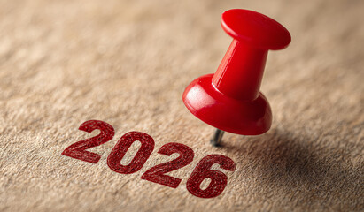 Close-up of red pushpin marking the year 2026 on a textured surface