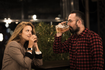 Friends enjoying a casual evening out, sharing drinks and conversation in a cozy bar setting, surrounded by warm lighting and a relaxed atmosphere, embracing a moment of leisure and connection