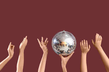 Female hands with disco ball on brown background