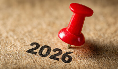 Close-up of red pin pointing at the year 2026 on a brown background