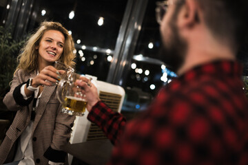 Smiling friends enjoying a night out at a cozy pub, toasting with beer glasses, surrounded by warm lighting and vibrant atmosphere, capturing a casual moment of fellowship and happiness.