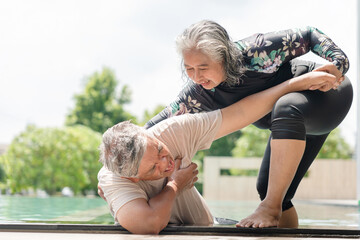 Elderly Woman Pulling Her Partner Out of a Swimming Pool in a Water Rescue or Emergency, Senior Couple Practicing Water Safety and Drowning Prevention Drills, Woman Helping Husband Out of the Pool