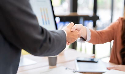 Close-up of a firm business handshake between two professionals over a desk, signifying a successful agreement, partnership, and collaboration.