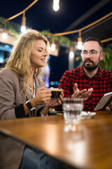 Casual cafe conversation between a woman and man during evening time highlighting friendship and connection
