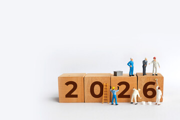 Transitioning from 2025 to 2026 with wooden blocks and miniature people. new year 2026 concept with white background.