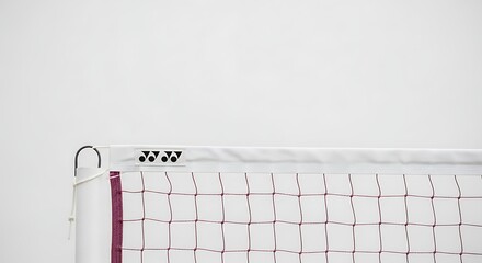 Close-up view of a white volleyball net with a maroon border and a white band featuring a black logo.