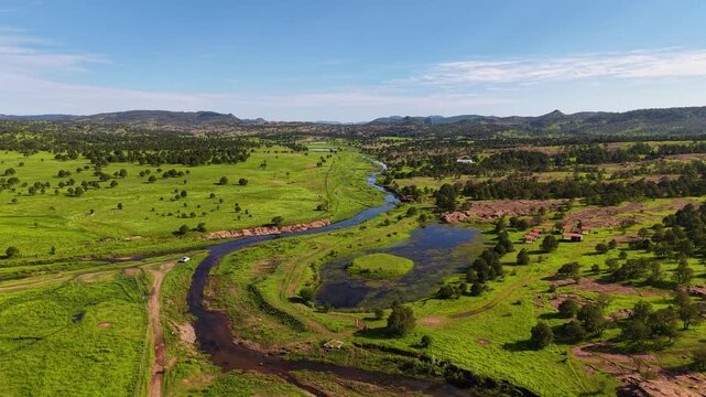 Un panorama esc&eacute;nico de un valle verde serca del pueblo de Yecora en el estado de Sonora, M&eacute;xico.  campo bajo un cielo azul con nubes blancas sobre la monta&ntilde;a y el r&iacute;o